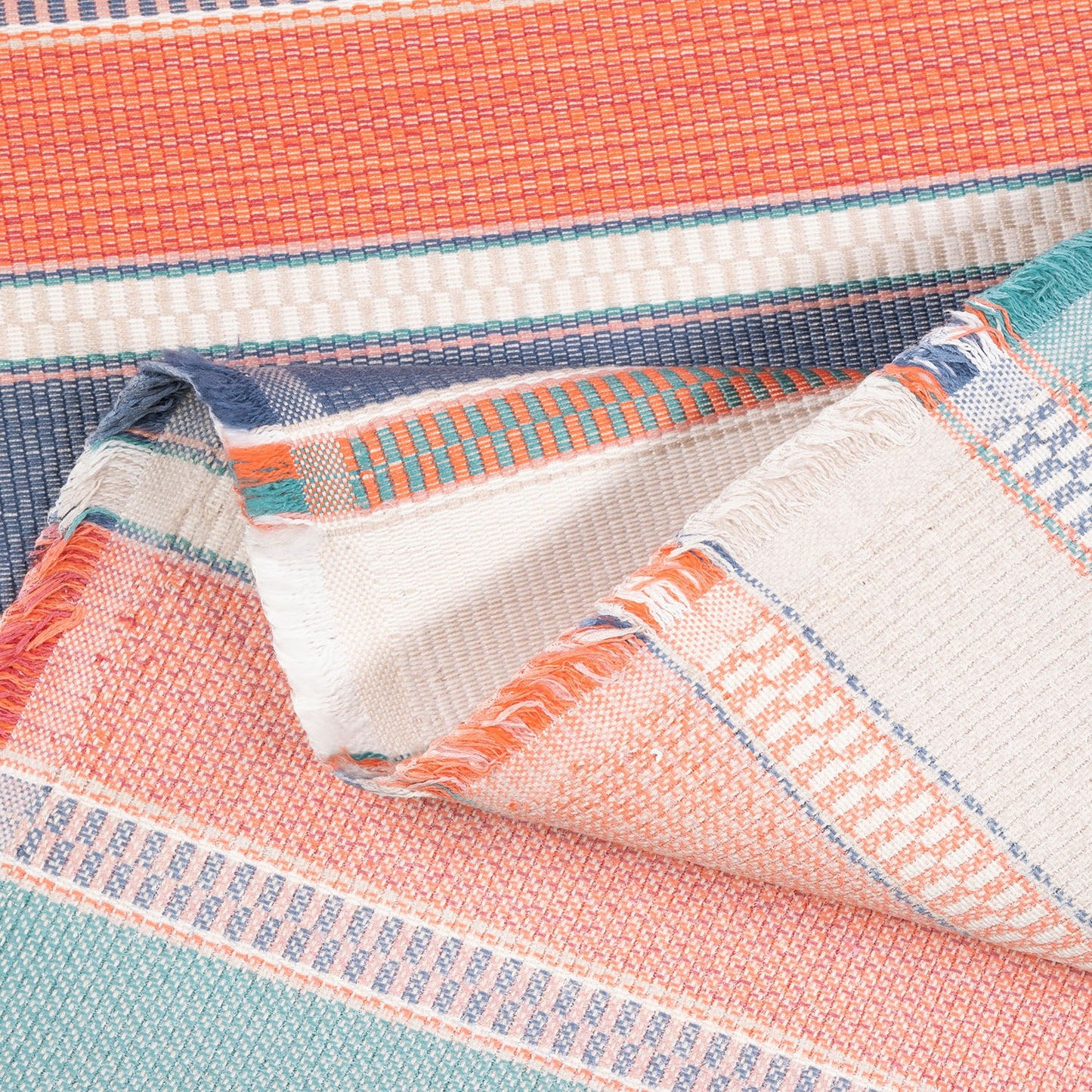 Close-up of a colorful woven fabric with stripes in orange, blue, and white.