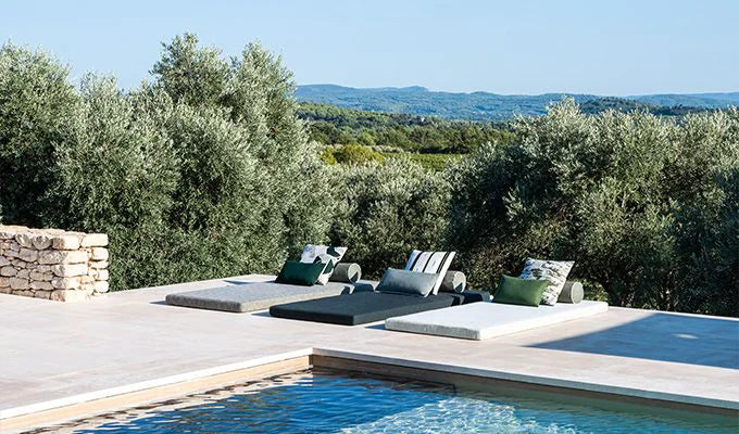 Pool area with lounge chairs and a scenic view of trees and landscape.