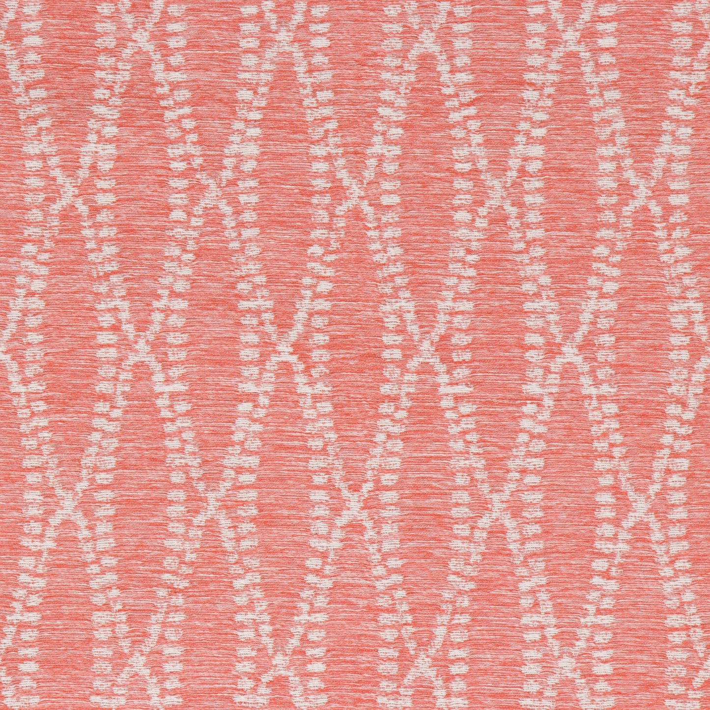 Close-up view of a fabric with a solid coral color and a pattern of white dots creating a geometric design