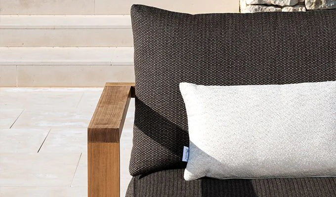 Gray pillow on a wicker chair with a neutral background