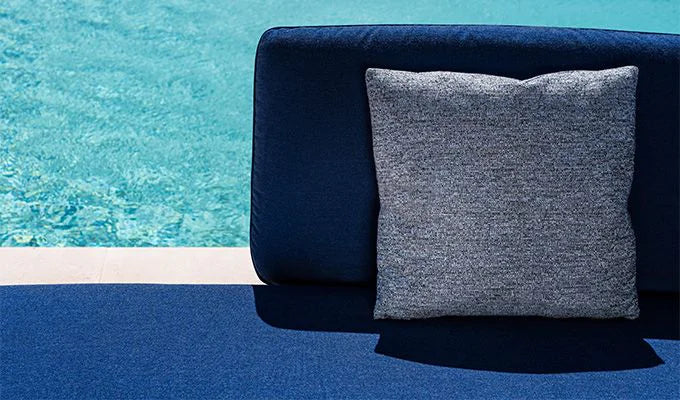 Gray pillow on a blue chair by a pool
