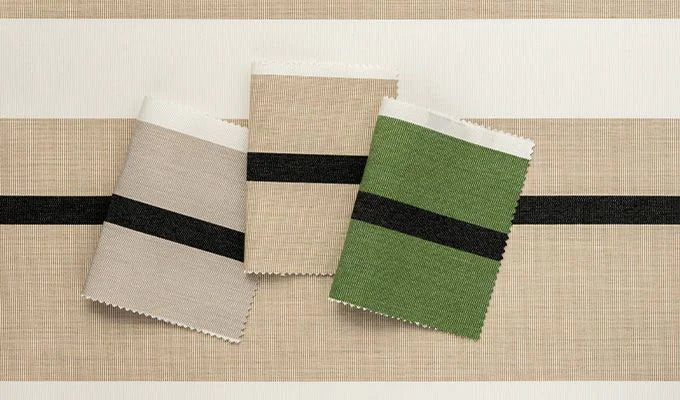 Fabric swatches in beige, green, and brown with black bands on a textured surface