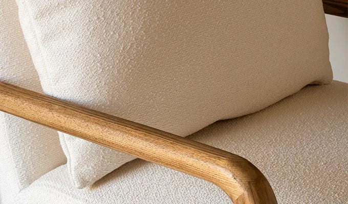 Close-up of a beige armchair with wooden armrest