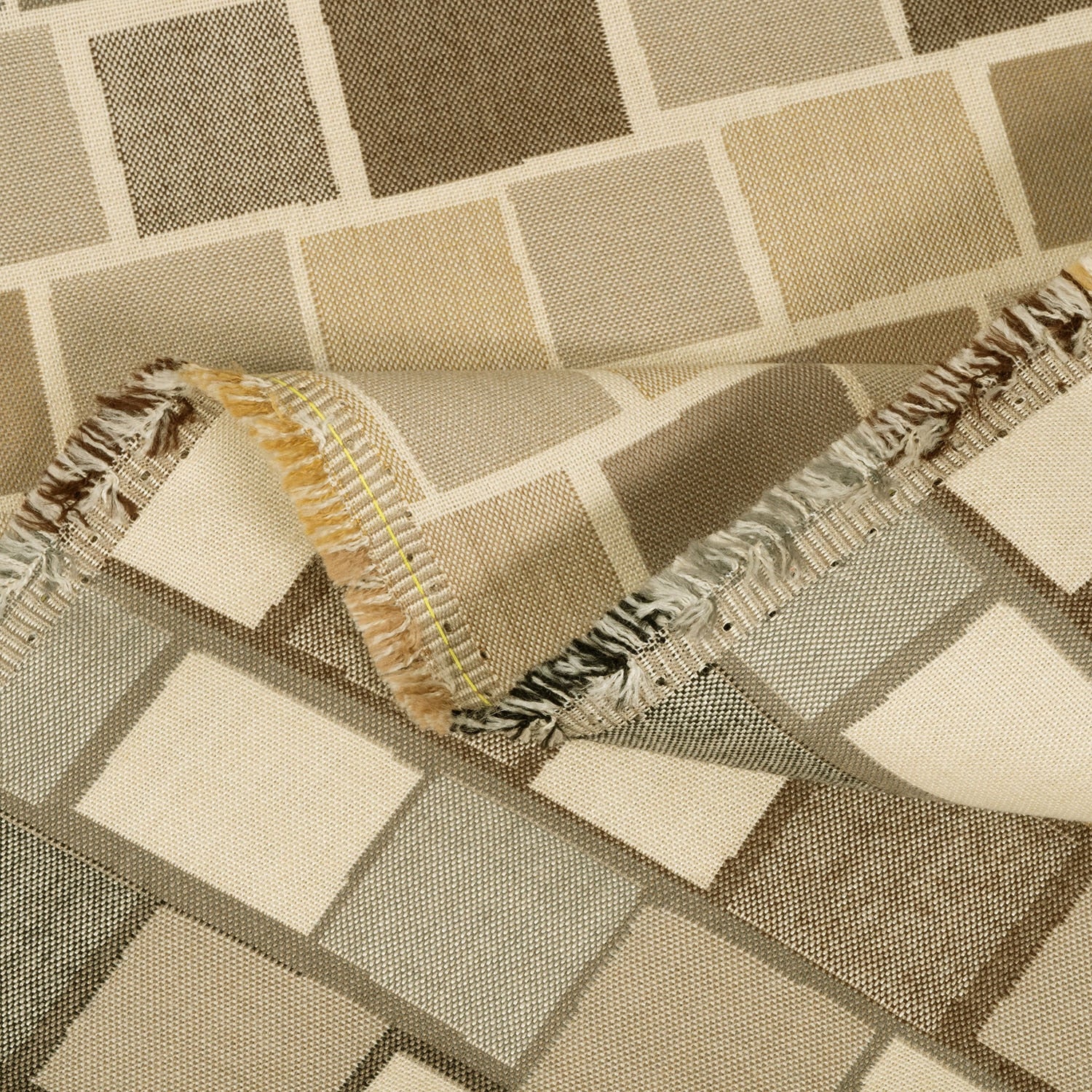Close-up of a textured fabric with geometric pattern and fringed edge.