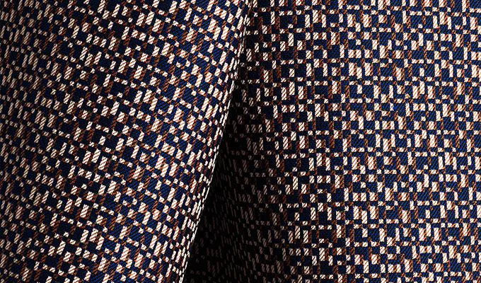 Close-up of patterned fabric with geometric design in navy, beige, and brown.