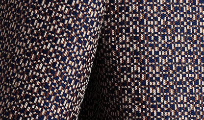 Close-up of patterned fabric with geometric design in navy, beige, and brown.