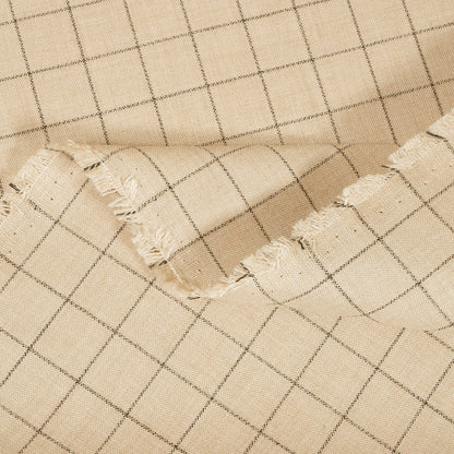 Close-up of beige fabric with a grid pattern and frayed edge.