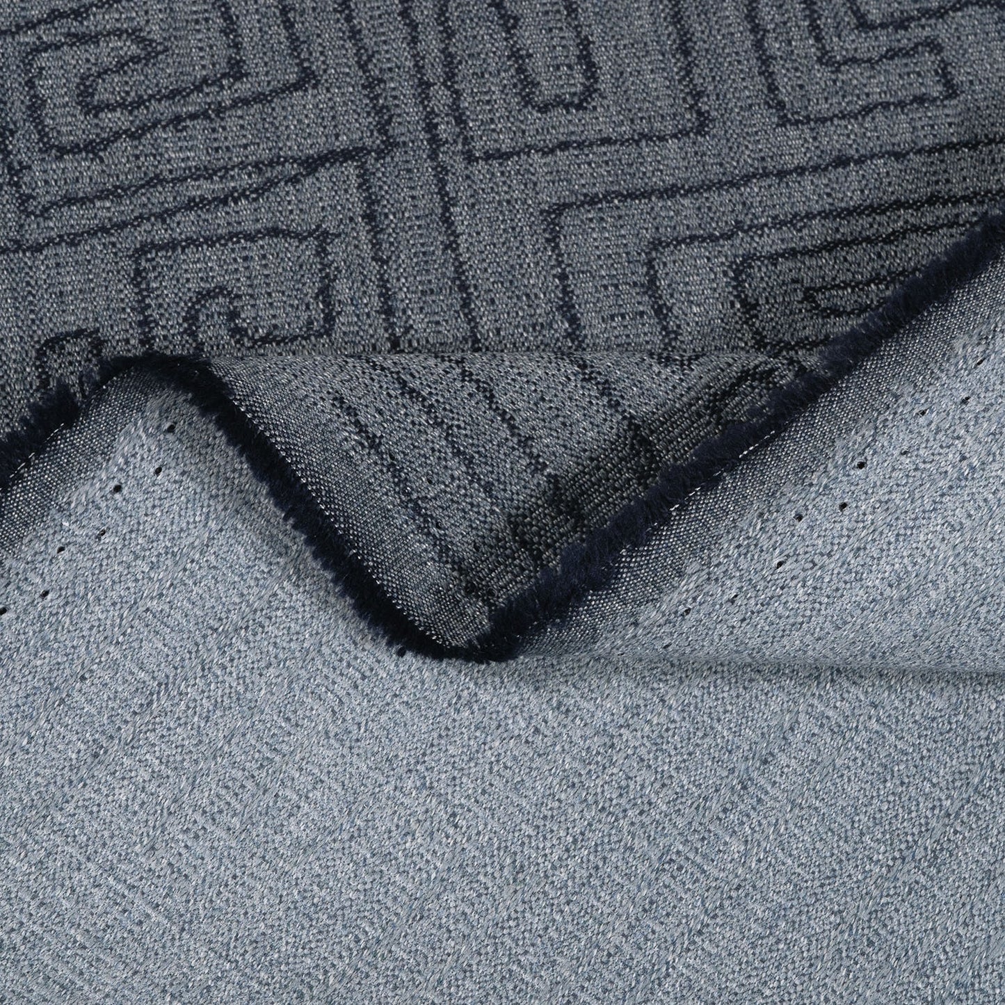 Close-up of a textured gray rug with a geometric pattern on a light gray surface.
