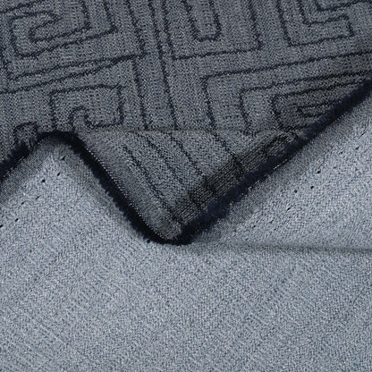 Close-up of a textured gray rug with a geometric pattern on a light gray surface.