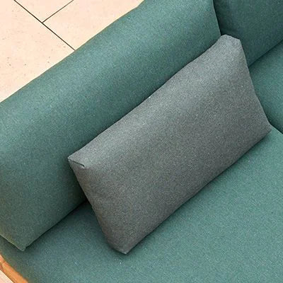 Teal sofa with a gray pillow on a tiled floor