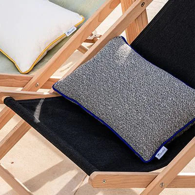 Two lounge chairs with cushions on a wooden deck by a pool.