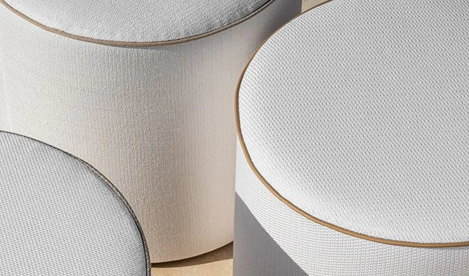 Close-up of round ottomans with textured surfaces and gold trim.