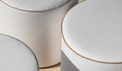 Close-up of round ottomans with textured surfaces and gold trim.