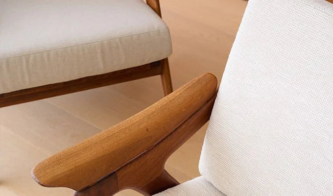 Close-up of a wooden armrest and beige cushion on a chair.