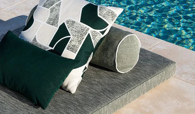 Decorative pillows on a lounge chair by a pool