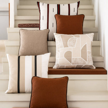 A collection of decorative throw pillows in various colors and patterns, styled on and around neutral-toned wooden stairs.