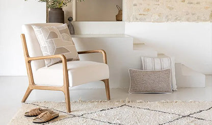 Beige armchair with wooden frame in a modern living room setting.