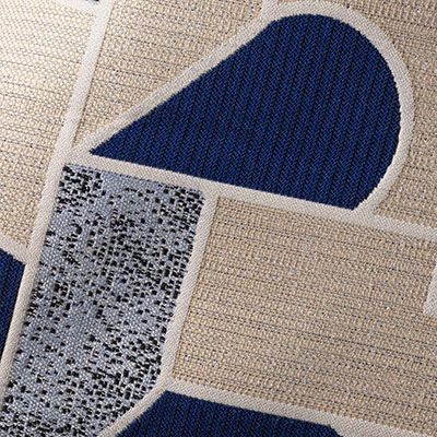 Close-up of a textured rug with geometric patterns in blue, beige, and gray.