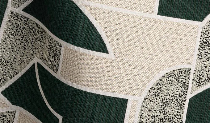 Close-up of a textured fabric with green, beige, and black patterns.