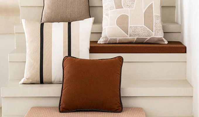 Decorative pillows on a wooden bench against a neutral wall