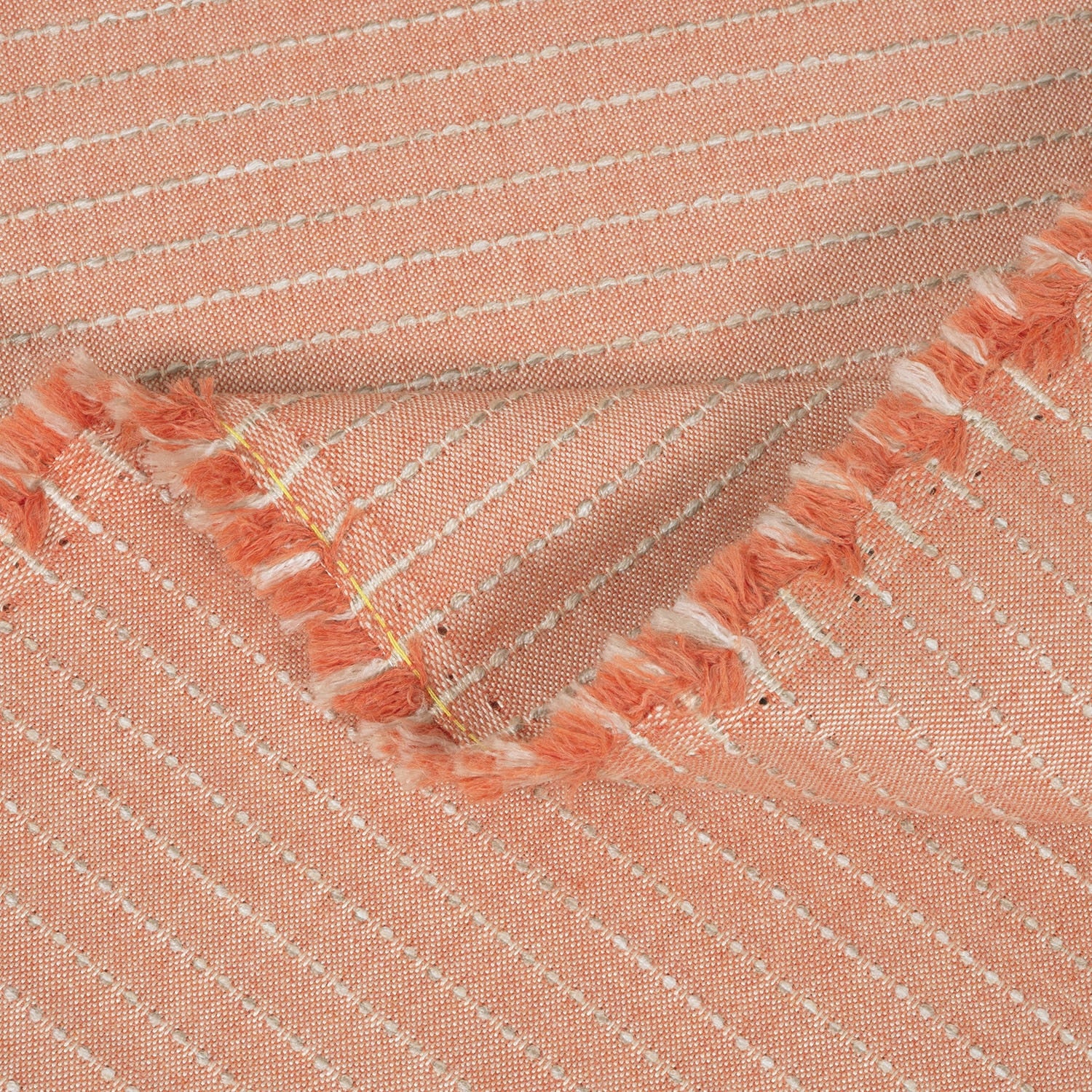 Close-up of peach-colored fabric with embroidered details