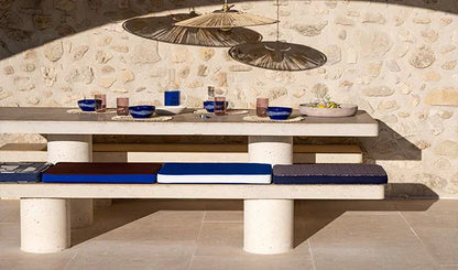 Dining table set with chairs against a stone wall