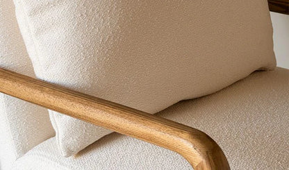 Close-up of a beige armchair with wooden armrest