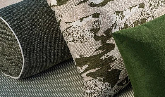 Three pillows on a textured surface with a camouflage pattern