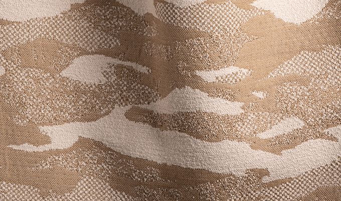 Close-up of a camouflage pattern fabric with brown, beige, and white colors.
